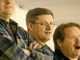 Prime Minister Harper stands amongst the other 'hockey dads' at the arena.